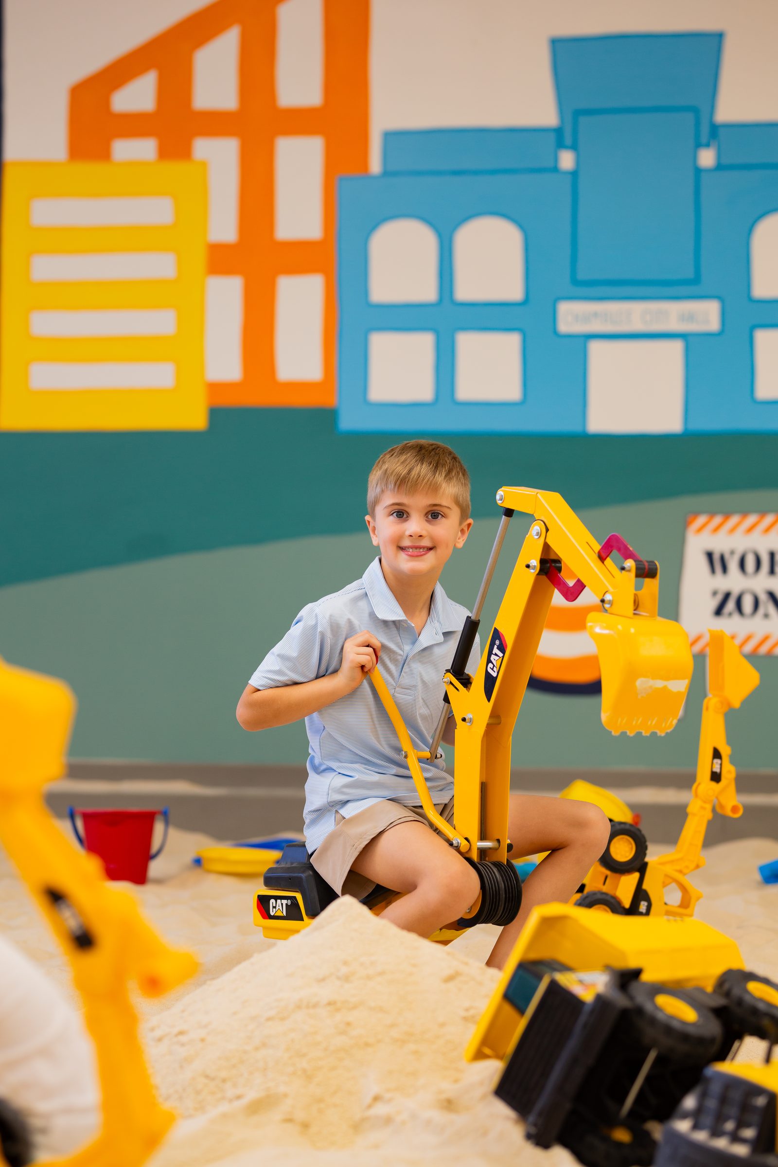Boy riding a CAT digger in the sand